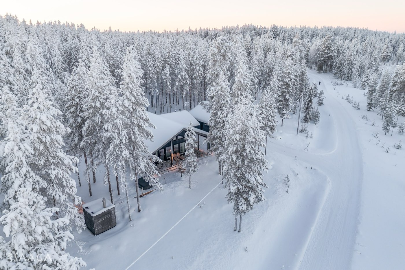 Aerial view of the house beside a quiet forest road at dusk