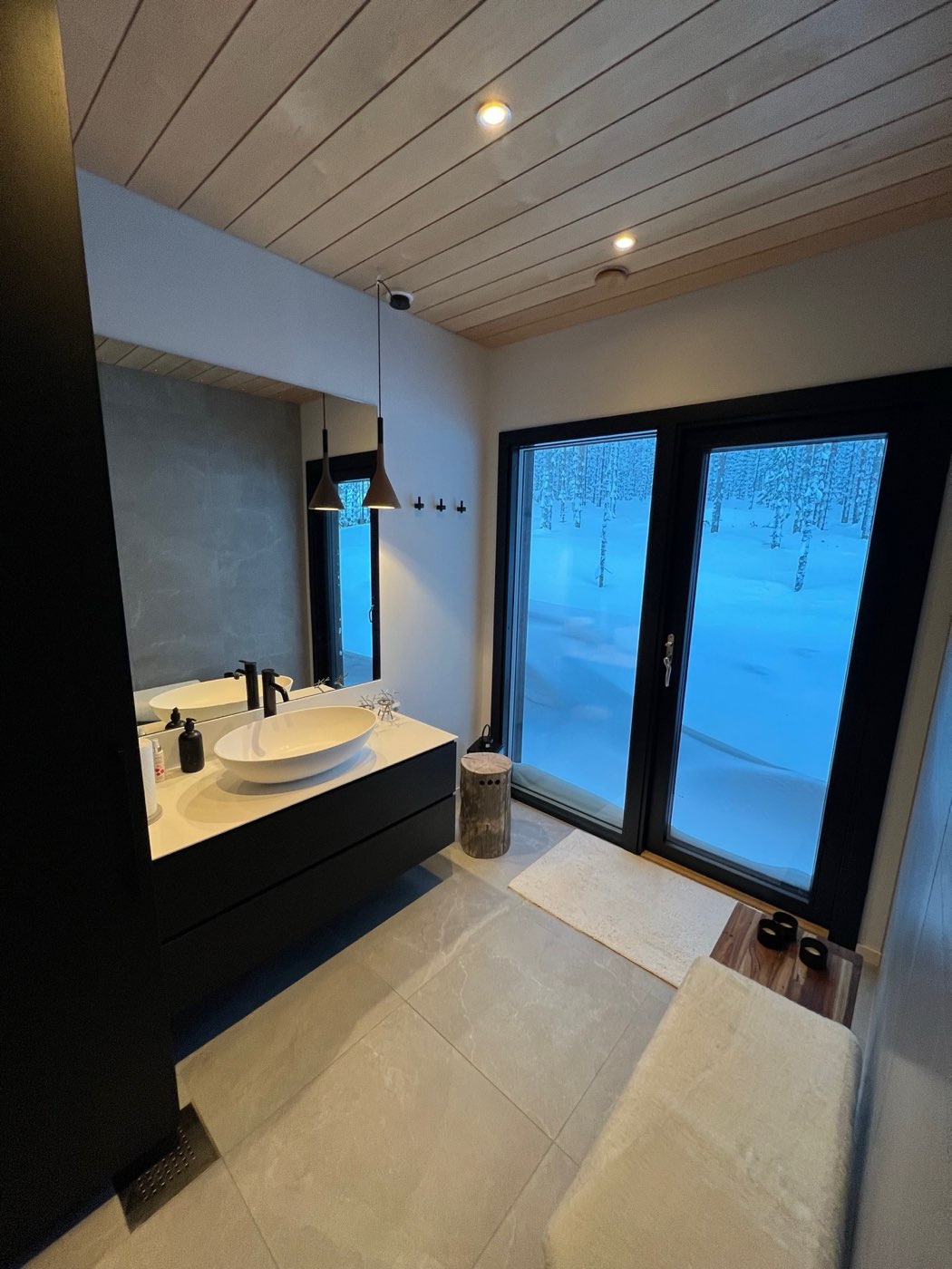 Bathroom with vessel basin and a glass door opening straight onto the snowy forest