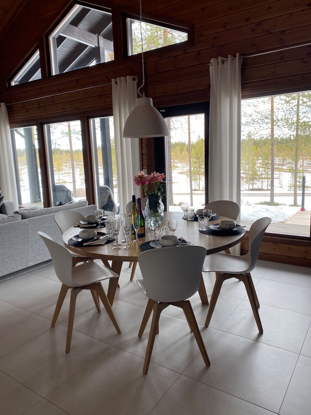 Round dining table with flowers by tall windows
