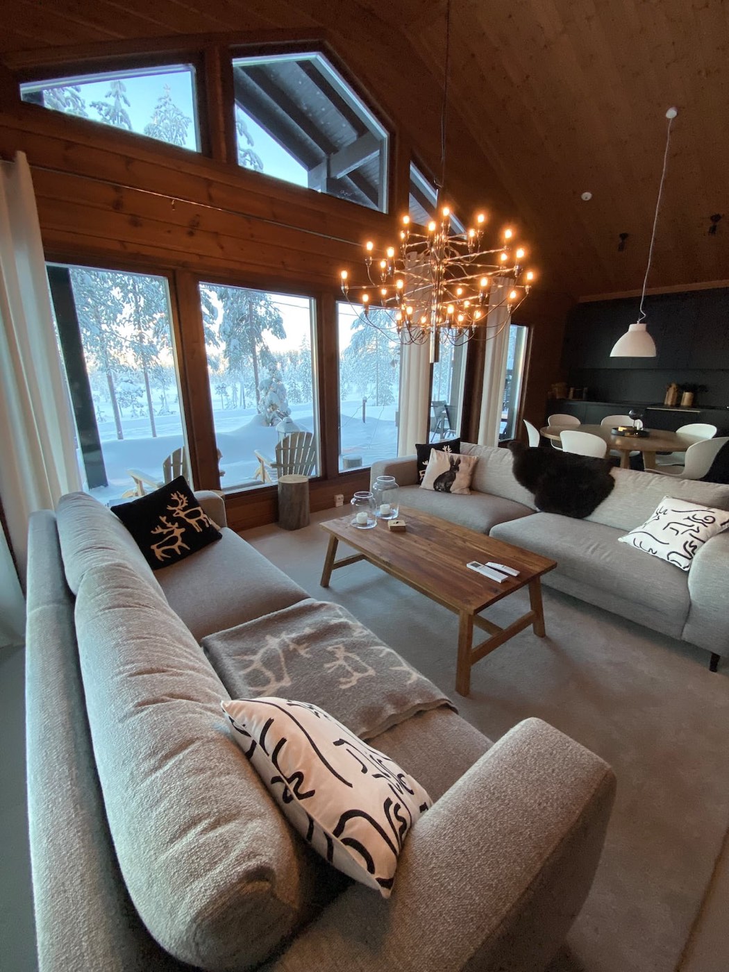 Sofas under a chandelier, facing floor-to-ceiling windows