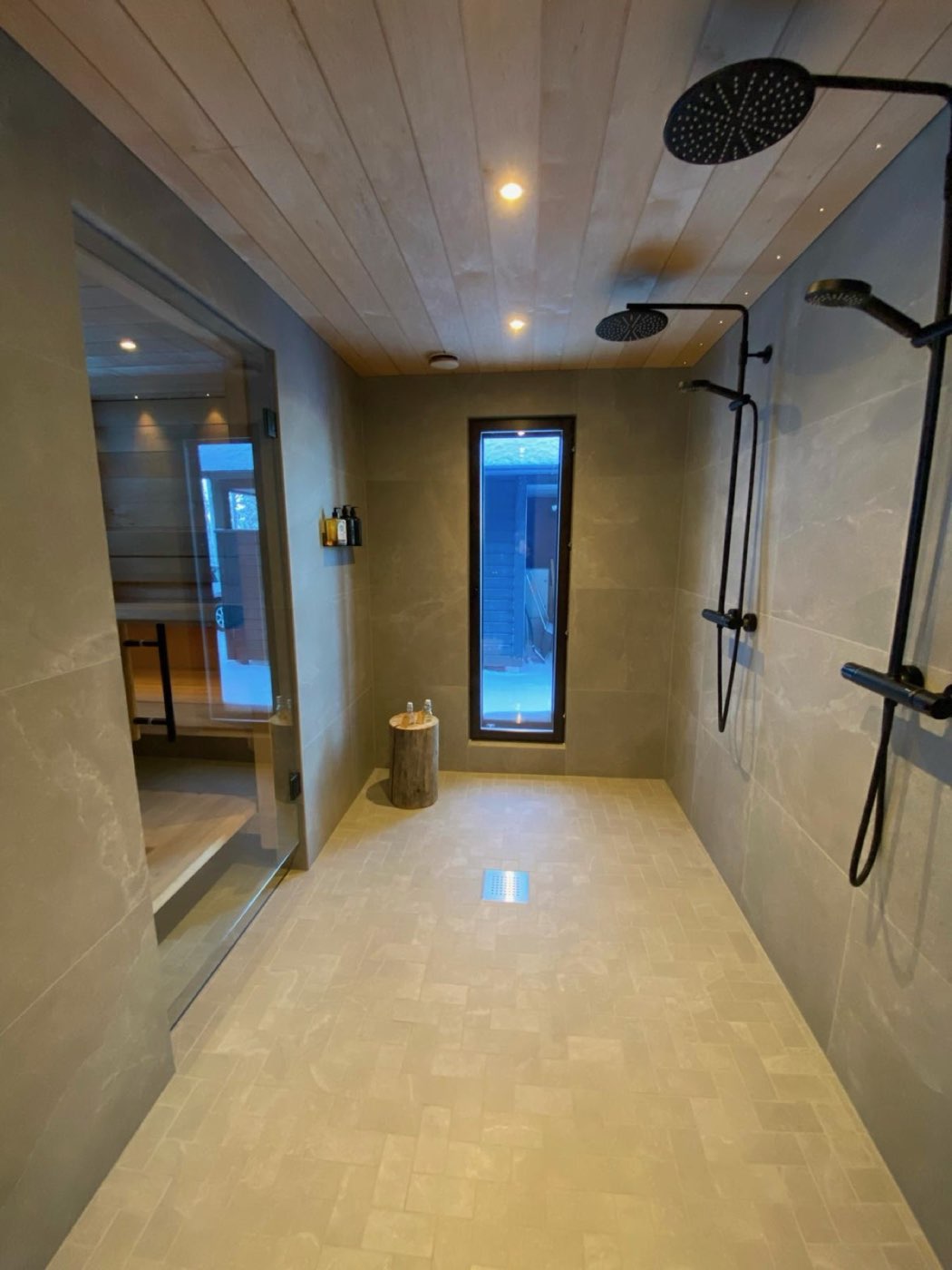 Walk-in shower room with twin black rain showers and glass sauna door