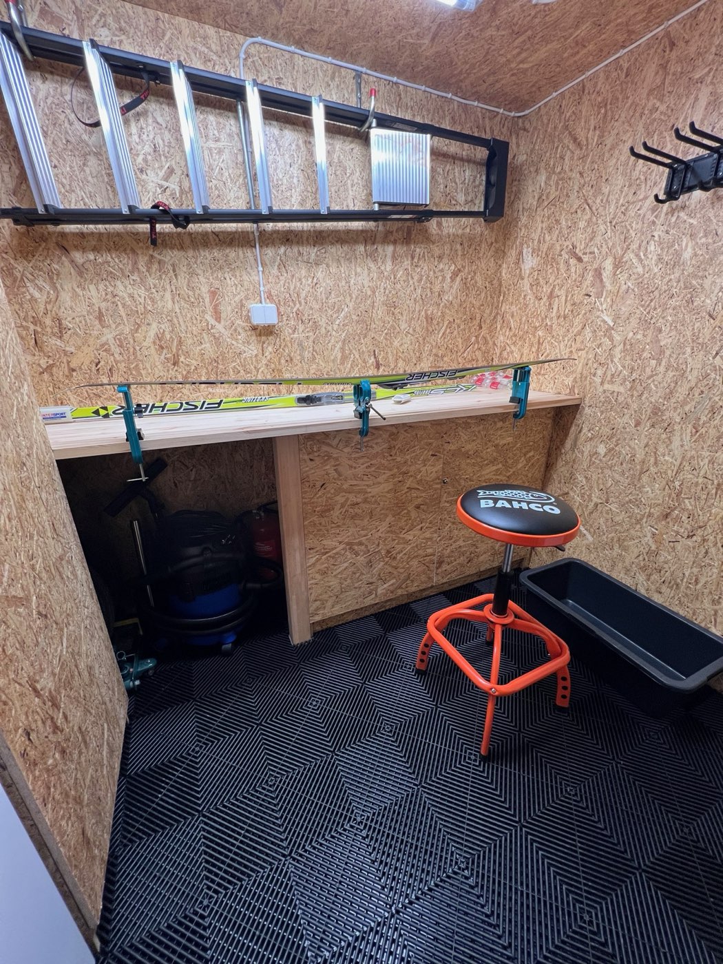 Ski maintenance room with waxing bench, ski rack, stool and storage